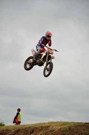 RUSSIA, SAMARA - JUNE 11: Motocross rider A. Nikishkin on a motorbike in flight removes the protective film from the glasses the Open class the Regional Motocross Championship on June 11, 2012 in Samara, Russiaのeditorial素材