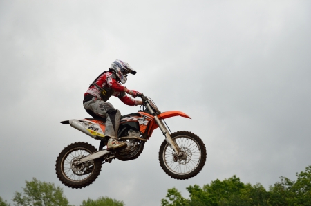 RUSSIA, SAMARA - JUNE 11: A leap over the hill, motorcycle racer S. Vintaev on the background a stormy sky the Open class the Regional Motocross Championship on June 11, 2012 in Samara, Russiaのeditorial素材