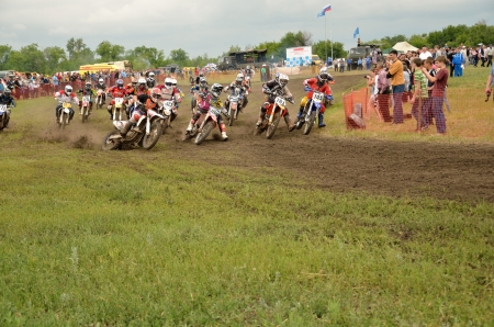 RUSSIA, SAMARA - JUNE 11: Motocross group of riders at the first corner after the start the Open class the Regional Motocross Championship on June 11, 2012 in Samara, Russiaのeditorial素材