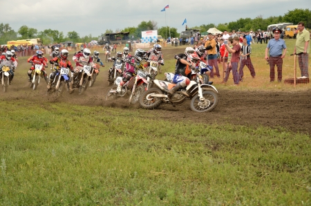 RUSSIA, SAMARA - JUNE 11: Group of riders the start  holeshot parts in the first corner the Open class the Regional Motocross Championship on June 11, 2012 in Samara, Russiaのeditorial素材