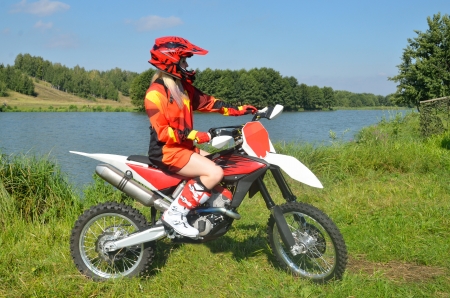 Girl with drawn feet in a red jersey and helmet, sitting on a sport bike for motocrossの写真素材