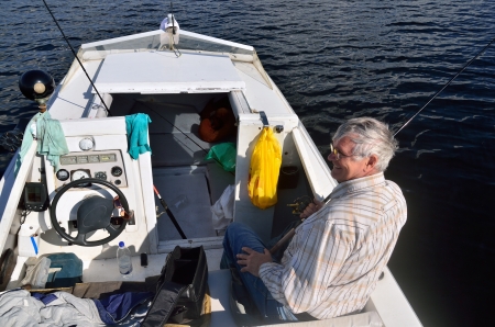 Fisherman man sits in the boat in hands a spinningの写真素材