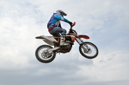 The spectacular jump motocross racer on the background a stormy skyの写真素材