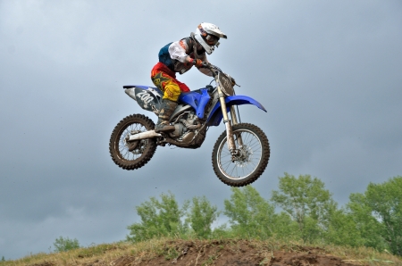 RUSSIA, SAMARA - JUNE 11: A leap over the hill, motorcycle racer A. Ukolov on the background a stormy sky the Regional Motocross Championship on June 11, 2012 in Samara, Russiaのeditorial素材