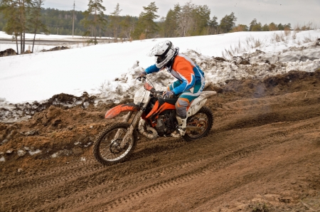 MX racer rides a motorcycle going down the motocross track of snow and sandの写真素材