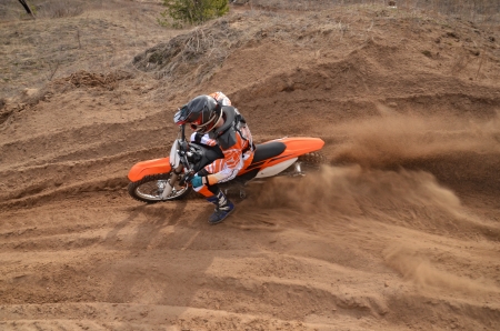 The MX driver put the right foot forward at the beginning of a deep rut turning sandy motocross trackの写真素材