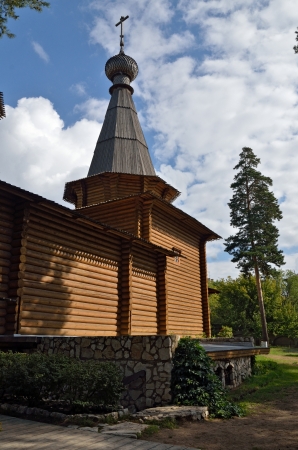 Tower the angular from logs with a dome and cross on a background of pine trees and skyの写真素材