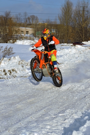 Winter motocross rider rides on the rear wheel on the snow-covered roadの写真素材