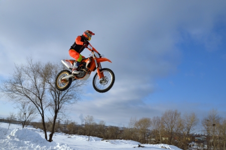 high flying motorcycle racer on the background of the snow drifts and of cloudsの写真素材