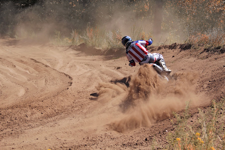 Entrance to the turning the sandy track of motocross racer with a slope of a motorcycle shot from behindの写真素材