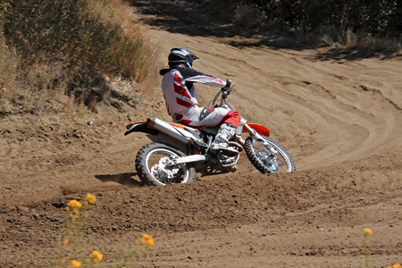MX rider on a motorcycle rides cornering along the sandy furrow motocross trackの写真素材