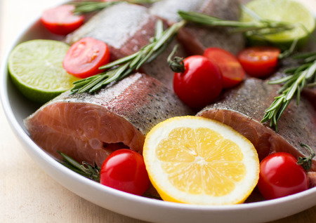 trout baking dish with lemon, lime, rosemary and tomatoesの写真素材