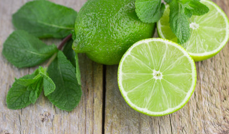 Juicy ripe limes and mint on wooden table
