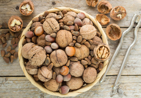 Hazelnuts, walnuts and pine nuts in a wicker basket on a wooden table