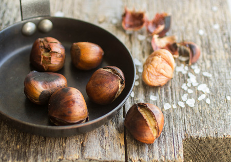 Roasted chestnuts on wooden table with coarse saltの写真素材