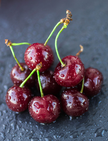 Ripe juicy cherries with water drops on dark backgroundの写真素材