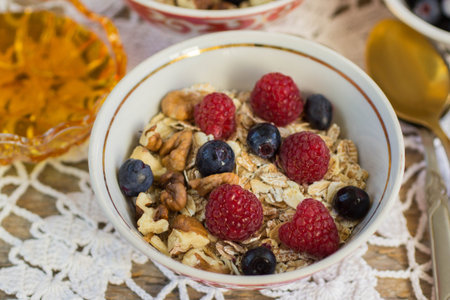 Healthy Breakfast. Muesli.  Homemade granola with raspberries, blueberries,  walnuts and honey. Shallow depth of fieldの写真素材