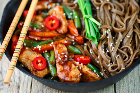 Buckwheat soba noodles with chicken, green beans, carrots, onions, chilli and sesame seedの写真素材