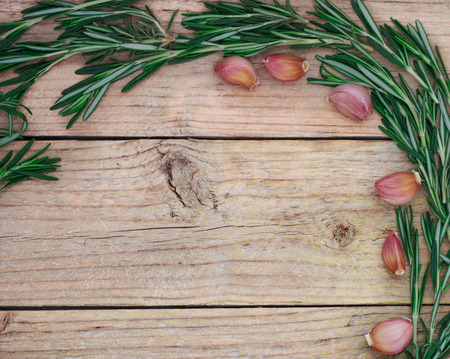 Sprigs of rosemary tied with twine and garlic on a dark wooden table. Copy space. Rustic styleの写真素材
