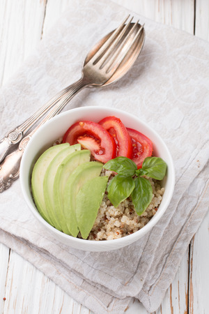 Warm quinoa salad with vegetables - avocado, red onion, tomatoes, bell pepper, Basil and olive oil. Healthy grain, super-duper. Selective focusの写真素材