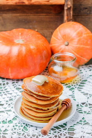 Homemade pumpkin pancakes with butter and honey on a white plate on the table. Useful, tasty Breakfast. Selective focusの写真素材