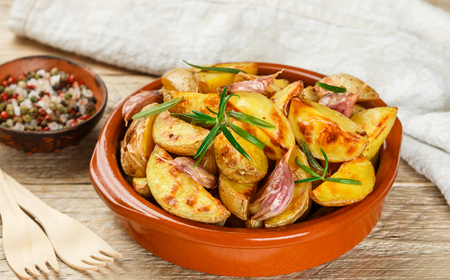 Potato wedges baked with garlic, rosemary and spices in a ceramic form. Selective focusの写真素材