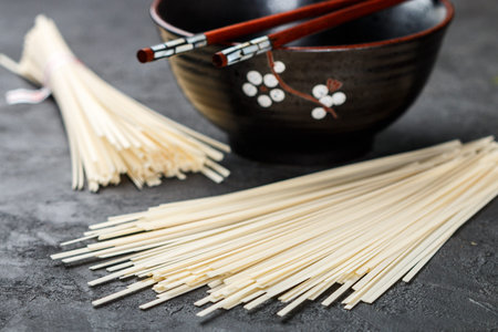 Raw Udon noodles for cooking Oriental and Asian cuisine on black background. Selective focus