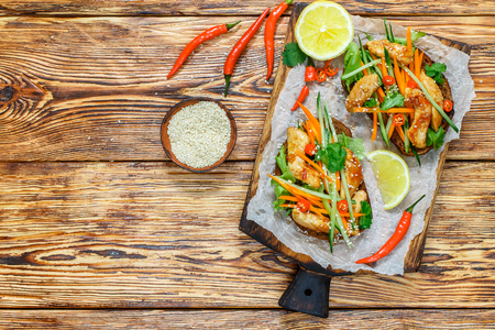 Asian sandwich with fried chicken and fresh vegetables-carrots, cucumber, chili pepper, cilantro and sesame. Selective focus. Top view and copy spaceの写真素材