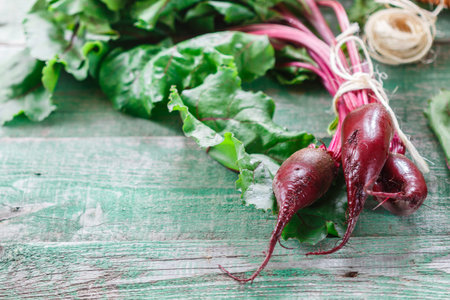 Organic red beets (beetroot) with green leaves on an old wooden table. Rustic style. Selective...
