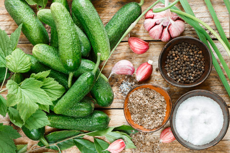 Ingredients for preservation on an old wooden table-cucumbers, garlic, dill seed, pepper, salt, seasonings and spices . Selective focusの写真素材