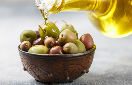 Mixed marinated olives (green, black and purple) in ceramic bowl  and olive oil. Selective focusの写真素材