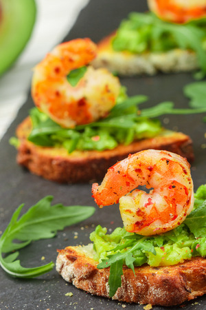 Appetizer of bread with seeds, shrimp, avocado and arugula. Crostini. Bruschetta. Sandwich. Antipasti. Selective focusの写真素材