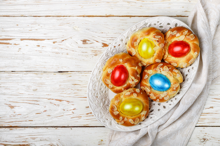 Traditional Easter buns decorated with eggs, almond petals and lemon zest. Sweet festive bread in the form of bird nests. Selective focus. copy space and top viewの写真素材
