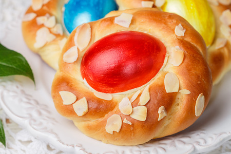 Traditional Easter buns decorated with eggs, almond petals and lemon zest. Sweet festive bread in the form of bird nests. Selective focusの写真素材