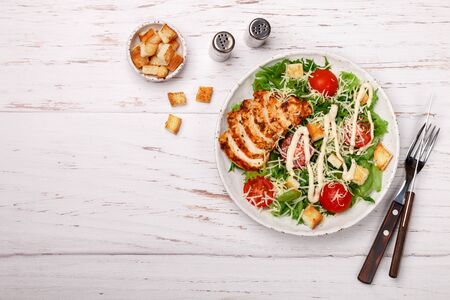 Healthy Grilled Chicken Caesar Salad with iceberg or lettuce, Cheese Parmesan, cherry tomatoes, bread Croutons and gourmet sauce. Selective focus, top view and copy spaceの写真素材