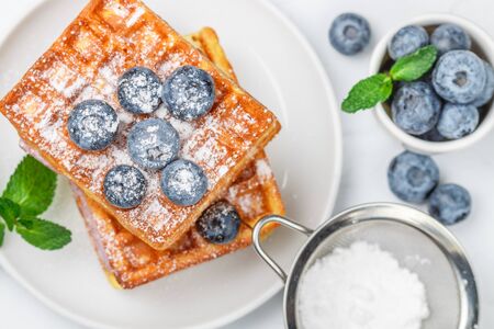 Traditional homemade Belgian (Viennese) waffles with fresh berries (blueberries) and powdered sugar. Delicious breakfast. Selective focus, top viewの写真素材