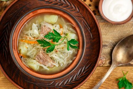Sauerkraut soup is a traditional dish of Russian, Ukrainian or Polish cuisine. Kapustnyak. Soup with beef, potatoes, onions, cabbage, parsley and spices. Selective focus, top viewの写真素材