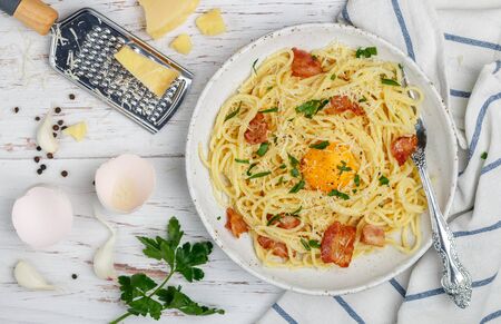 Pasta Carbonara. Spaghetti with bacon, egg and Parmesan cheese in a white plate on a wooden table. traditional Mediterranean (Italian) dish. Selective focusの写真素材