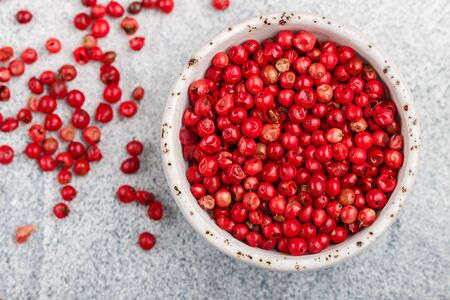 Pink Organic dried Peppercorns in a white bowl on a light concreteの写真素材