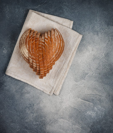 Sliced round loaf of rye bread in the shape of a heart on a gray linen napkin. Tasty and usefull...