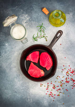 Raw Tuna fish steaks with sea salt, pink, green and black pepper and rosemary for grill or cooking in a cast iron pan. Prepare a delicious dinner. Selective focus and copy spaceの写真素材