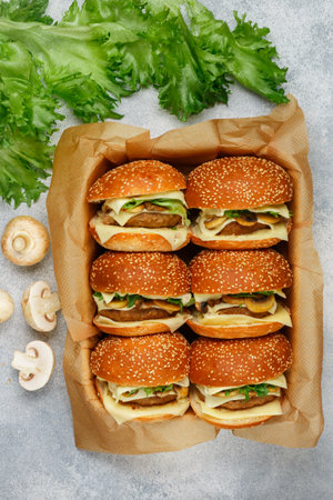 Delicious homemade burgers with beef or chicken cutlet, cheese, lettuce and fried mushrooms on sesame buns. Selective focus, top viewの写真素材