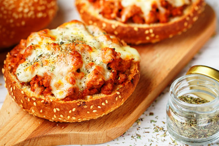 Freshly baked homemade mini pizza made of minced meat (beef, pork, chicken, turkey) with onions, garlic, tomatoes, mozzarella cheese and dry thyme on sesame buns. Rustic style. Selective Focusの写真素材