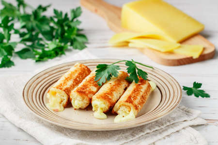 Fried rolls of bread and parmesan cheese with parsley on a plate on a white wooden background. Breakfast. Brunch. A delicious snack for gourmets. Selective Focusの写真素材