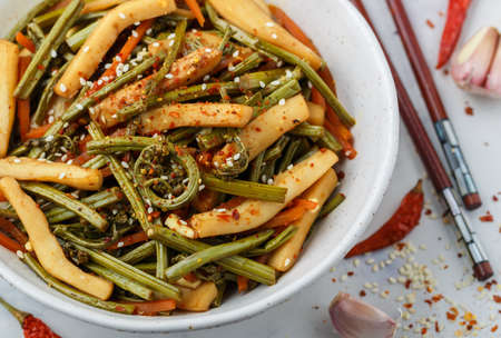 Sauteed bracken fern with squid, red pepper, carrot, garlic, soy sauce and sesame seeds. Delicious spicy seafood appetizer. Warm or cold salad close-up. Asian cuisine - Chinese, Japanese, Koreanの写真素材