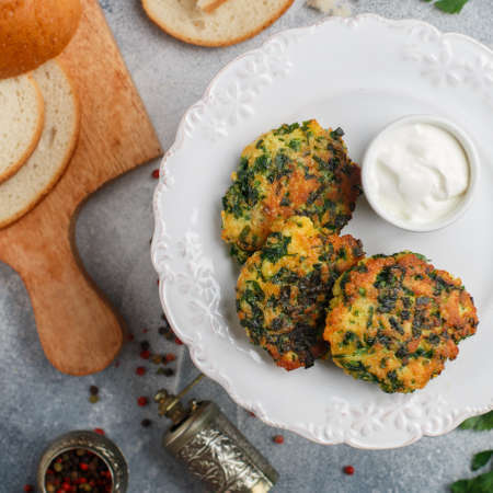 Vegetarian pancakes or cutlets with herbs (parsley, dill, cilantro, basil), eggs, walnuts and spices. Delicious healthy breakfast on a white plate. Served with yoghurt. Iranian cuisine. selective focusの写真素材