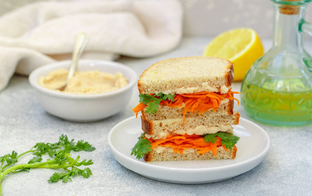 Delicious spicy sandwich of whole grain bread with fried carrots, hummus, garlic and cilantro. Healthy breakfast. Vegetarian food. selective focusの写真素材