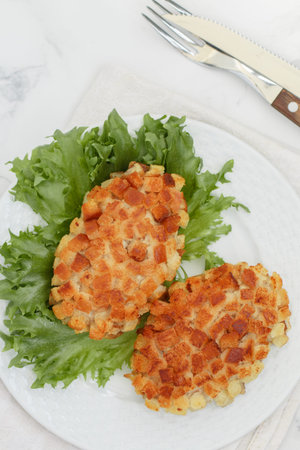 Pozharsky cutlets and lettuce leaf in a white plate on a marble background. selective focus, top viewの写真素材