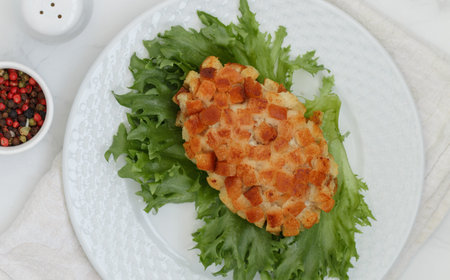 Pozharsky cutlets and lettuce leaf in a white plate on a marble background. selective focus, top viewの写真素材
