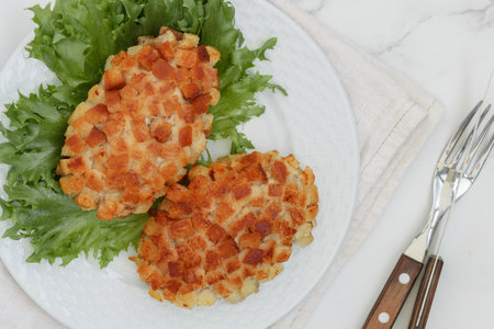 Pozharsky cutlets and lettuce leaf in a white plate on a marble background. selective focus, top viewの写真素材